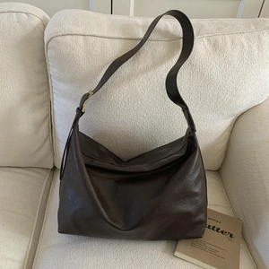 Detail of deep brown large tote bag with adjustable wide strap and gold hardware