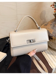 Chic cream beige crossbody bag with silver twist lock held by a model in soft natural light