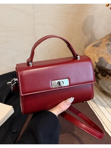 Detail of burgundy leather rectangular handbag with silver metal twist lock and handle