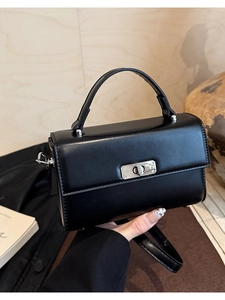 Detail shot of black faux leather handbag with silver rotating metal lock and round handle