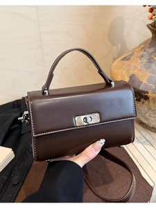Detailed view of a vintage brown leather handbag with elegant silver metal twist lock clasp