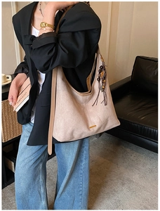 Détail du grand sac cabas beige en daim avec pendentif décoratif en perles de bois