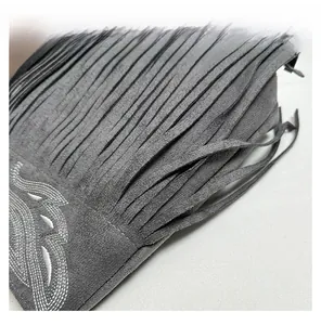 Detailed view of grey suede tassel bag featuring intricate silver thread embroidery