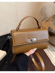 Close-up of brown vintage crossbody bag featuring a polished silver metal twist lock