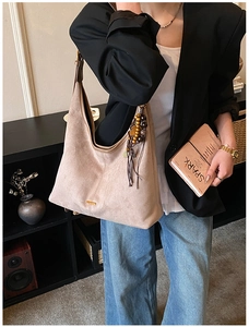 Détail d'un sac hobo en daim beige doté d'un gland décoratif en perles de bois