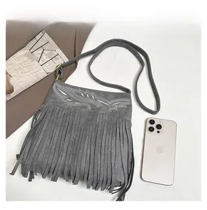 Detail view of grey faux suede crossbody bag with embroidery, fringe, and size comparison