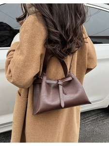 Detail of dark brown leather bucket bag with decorative knot showing the textured surface