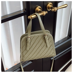 Détail de la texture tressée du sac à bandoulière vert clair aux accents dorés