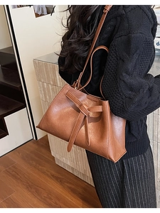 Detailed view of brown caramel leather bucket bag with crisscross strap decoration