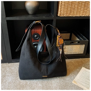 Détail du sac cabas en daim noir avec pendentif en perles de bois et bandoulière en cuir
