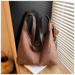 Détail d'un sac hobo marron avec texture en daim, bordure en cuir et charme bohème