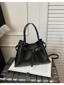 Detail view of black vintage bucket bag with knotted leather decor on a silver suitcase