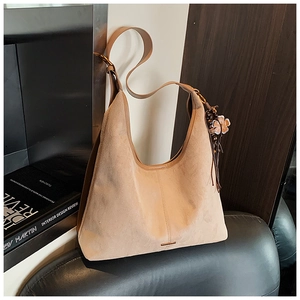 Détail du cabas en daim beige avec pendentif floral rétro et finitions en cuir marron