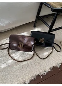 Détail de sacs bandoulière carrés avec boucles dorées géométriques et bandoulière chaîne