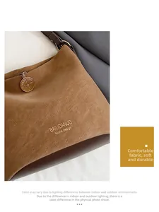 Detail of brown suede tote bag with gold logo lettering and metallic pendant