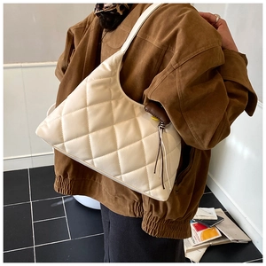 Detail of quilted hobo shoulder bag in cream white with stylish side tassel decor