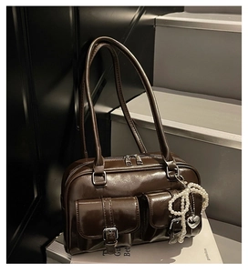 Detail of dark brown leather bowling bag showing front pockets and pearl heart pendant