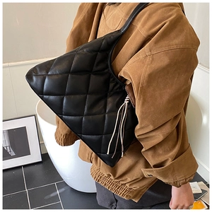 Close-up of black quilted shoulder bag with elegant tassel detail and soft texture