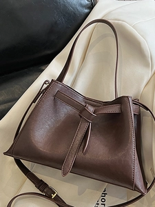 Vintage brown leather bucket bag with decorative knot and adjustable shoulder strap