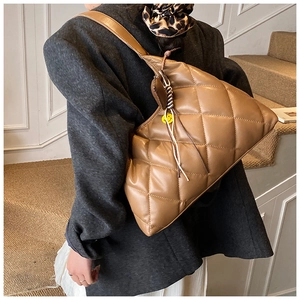 Detail of brown quilted hobo bag with wide strap and a yellow smiley face charm