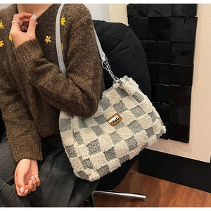 Dettaglio della borsa tote invernale a scacchi in peluche con catena e etichetta in cuoio