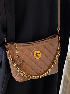 Quilted dark brown shoulder bag with gold chain and turn-lock closure on black suit