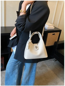 Detail of creamy white litchi pattern leather bucket bag with metal twist lock closure