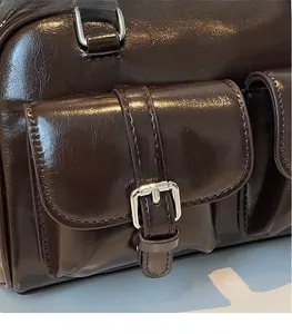 Detailed macro view of dark brown glossy leather texture and silver buckle pockets