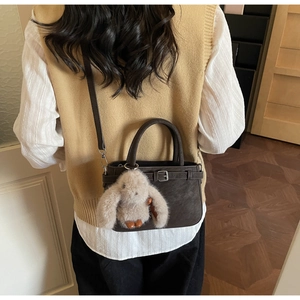 Détail du sac à main en cuir marron foncé avec boucle argentée et charm lapin en peluche