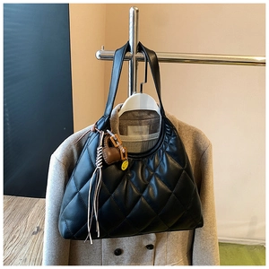 Detail of black quilted tote bag with decorative charms hanging on a metal rack