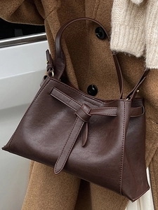 Retro dark brown leather bucket bag with decorative knot and slim strap for winter