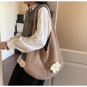 Detail shot of a brown crochet tote bag with a white flower applique and knit texture