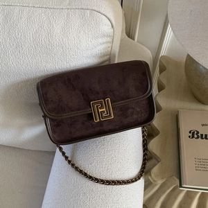 Détail de la bandoulière en daim marron avec chaîne dorée et boucle métallique vintage
