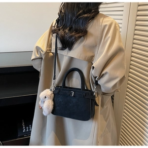 Détail du sac à main noir mat avec texture en daim et pendentif lapin en peluche mignon
