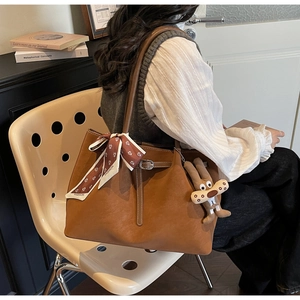 Detail of brown faux leather tote bag with printed silk scarf and rabbit plush charm