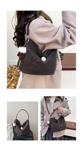 Detail of dark brown leather tote bag with gold charm and plush glove accessory