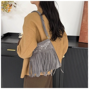Detail of grey suede shoulder bag with vintage embroidery and long fringe tassels