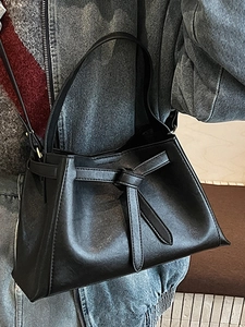 Minimalist black bucket bag in premium leather finish with unique knotted belt detail