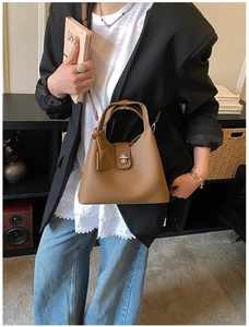 Brown lychee leather bucket bag with silver twist lock shown on a model in a casual street style