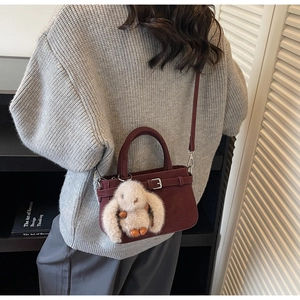 Détail du sac à bandoulière bordeaux mat avec breloque lapin en peluche et boucle argentée