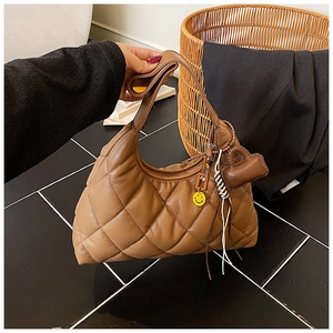 Detail of brown quilted hobo bag featuring heart and smiley face charms on strap