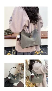Detail of green litchi textured shoulder bag with golden logo and cute charms on a strap