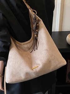 Grand sac cabas beige en suédine avec barre métallique et pompon sur mannequin