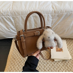 Détail d'un sac à main marron avec boucle décorative et breloque lapin en peluche doux