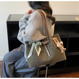 Detail view of large olive green suede tote bag with scarf and bunny charm accessory