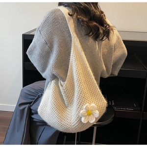 Macro detail of creamy white crochet tote bag with large daisy flower on shoulder bag