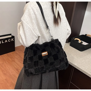 Dettaglio della borsa tote in peluche a scacchi neri con logo in pelle e catena in metallo