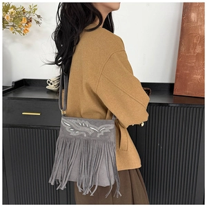 Close-up of vintage grey fringe bag featuring white leaf embroidery and suede texture
