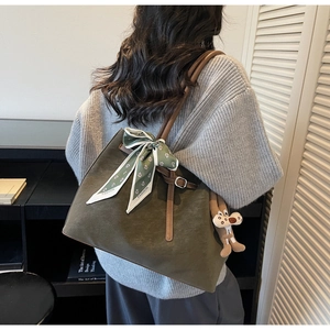 Detail of olive green suede tote bag with brown leather strap and floral scarf decor