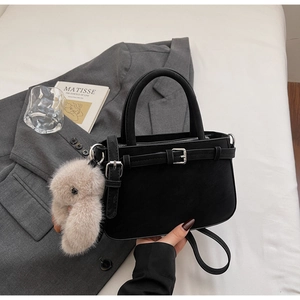 Détail d'un sac à main noir mat avec boucle argentée et charm lapin en peluche amovible